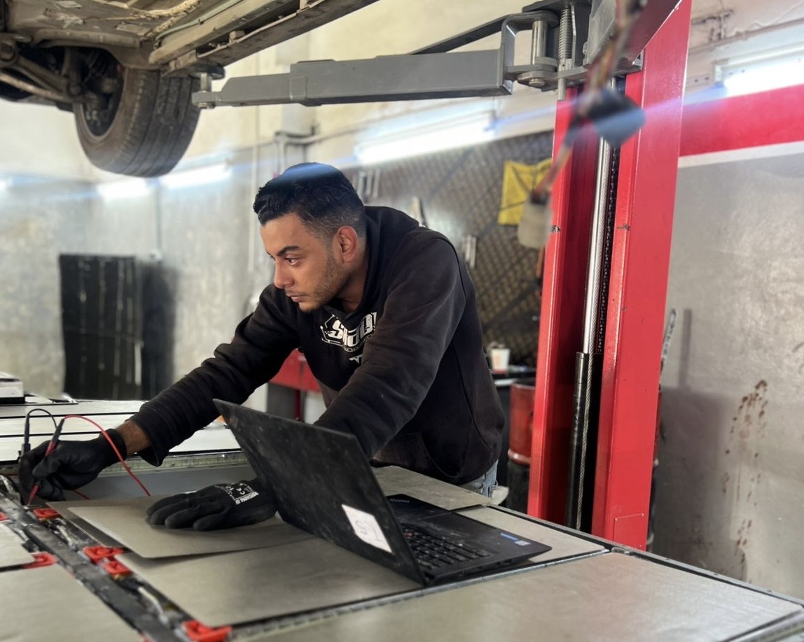 Un homme travaille sur de grandes batteries usagées de VE dans un atelier à Amman