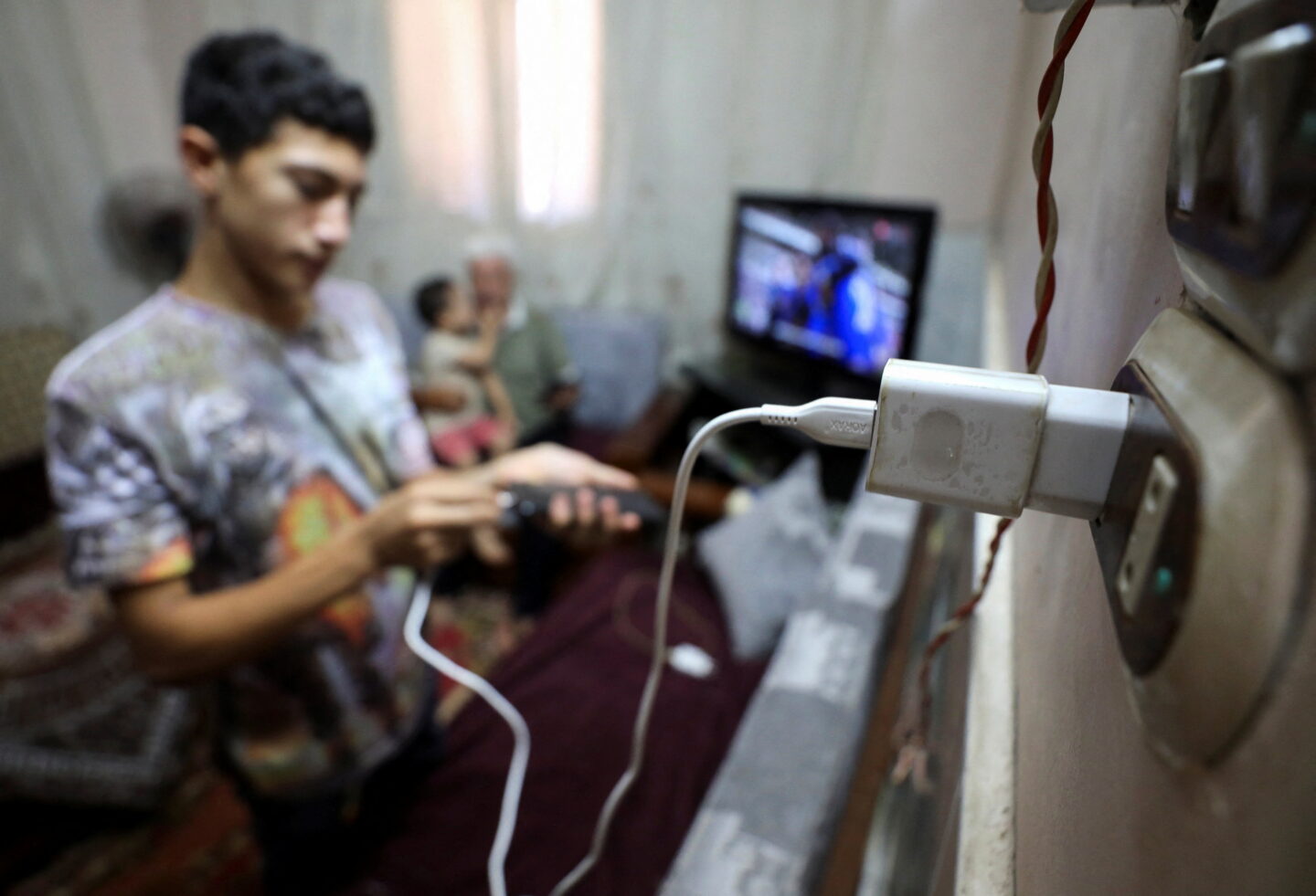 Un homme recharge son téléphone grâce aux panneaux solaires au-dessus de sa maison dans le village d'Al-Basaysa alors que le pays connaît des coupures d'électricité répétées en 2024