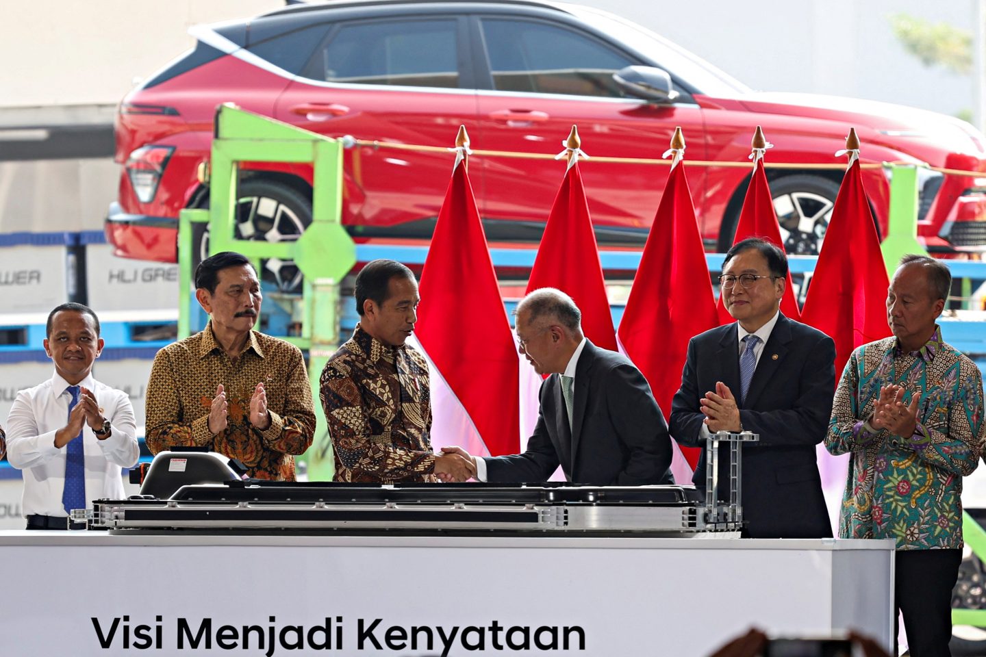 Former Indonesian President Joko Widodo shakes hands with Hyundai Motor Group Executive Chair Euisun Chung on a stage with Indonesia flags in the background during the launching of Indonesia's first EV battery cell production plant in Karawang, West Java province